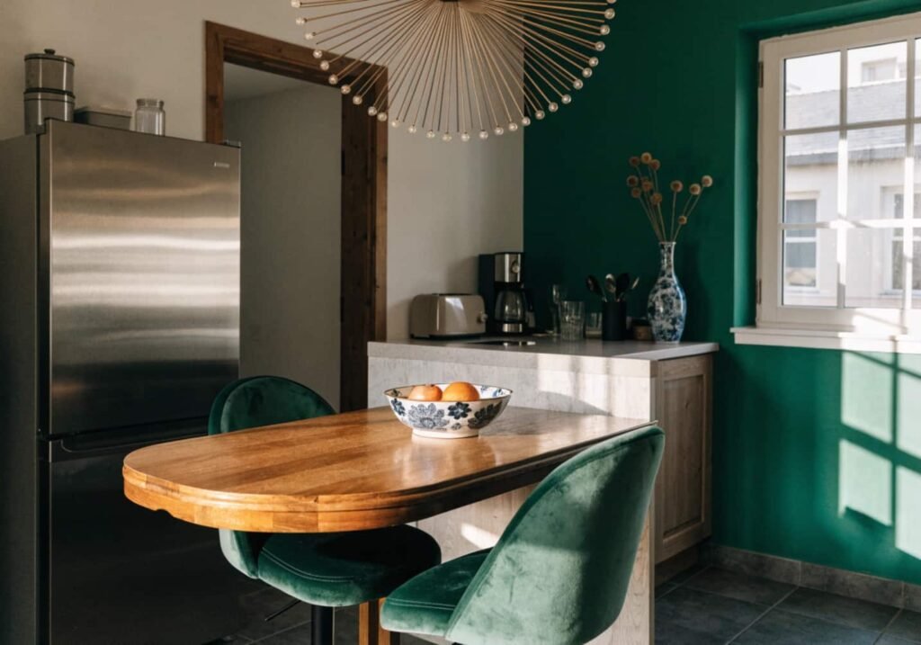 Emerald accent wall and sunburst pendant light in budget-friendly Neo Art Deco kitchen