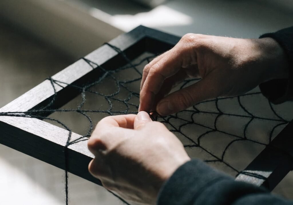 Step-by-step process of wrapping yarn into a spider web craft using a picture frame.