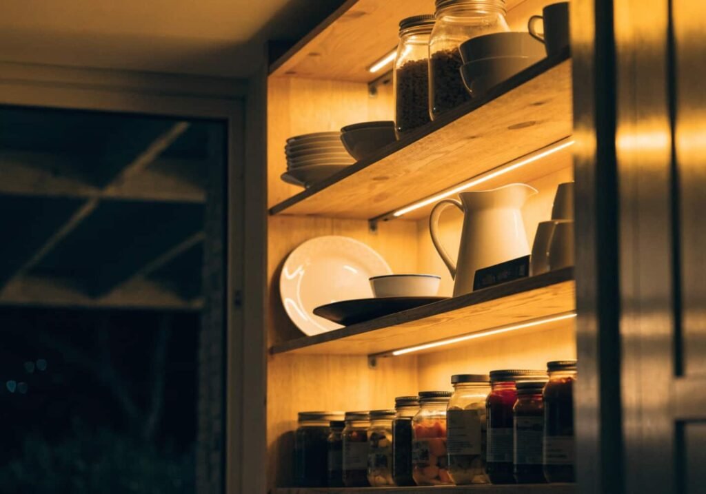 Warm LED lighting highlighting open kitchen shelves at night.