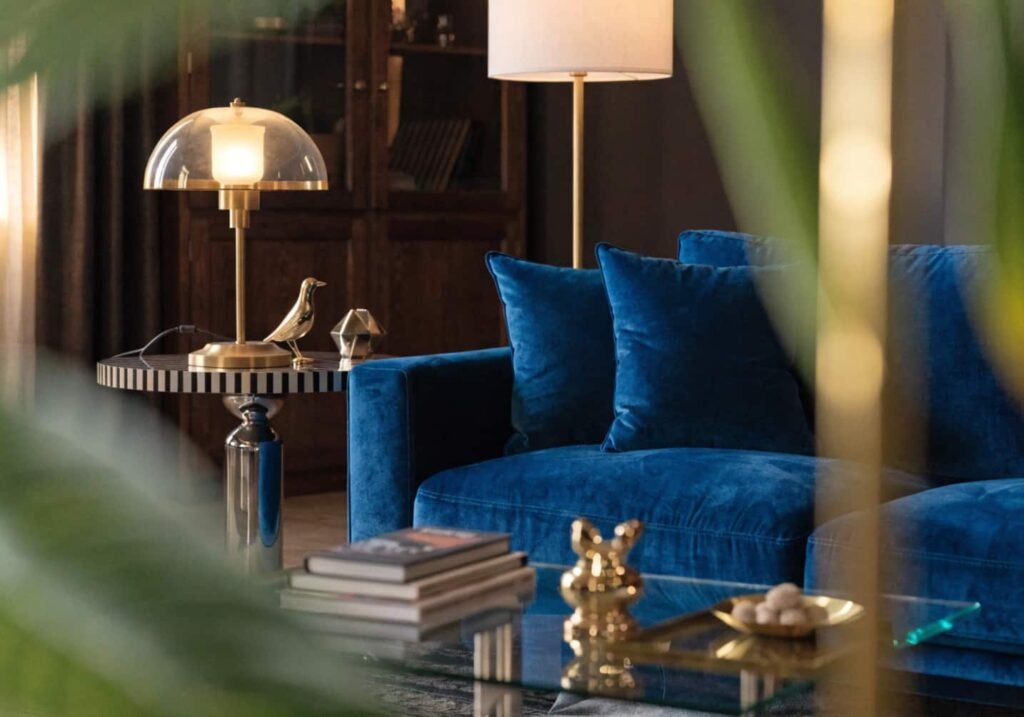 Deep blue velvet couch styled with gold accents in a luxury living room