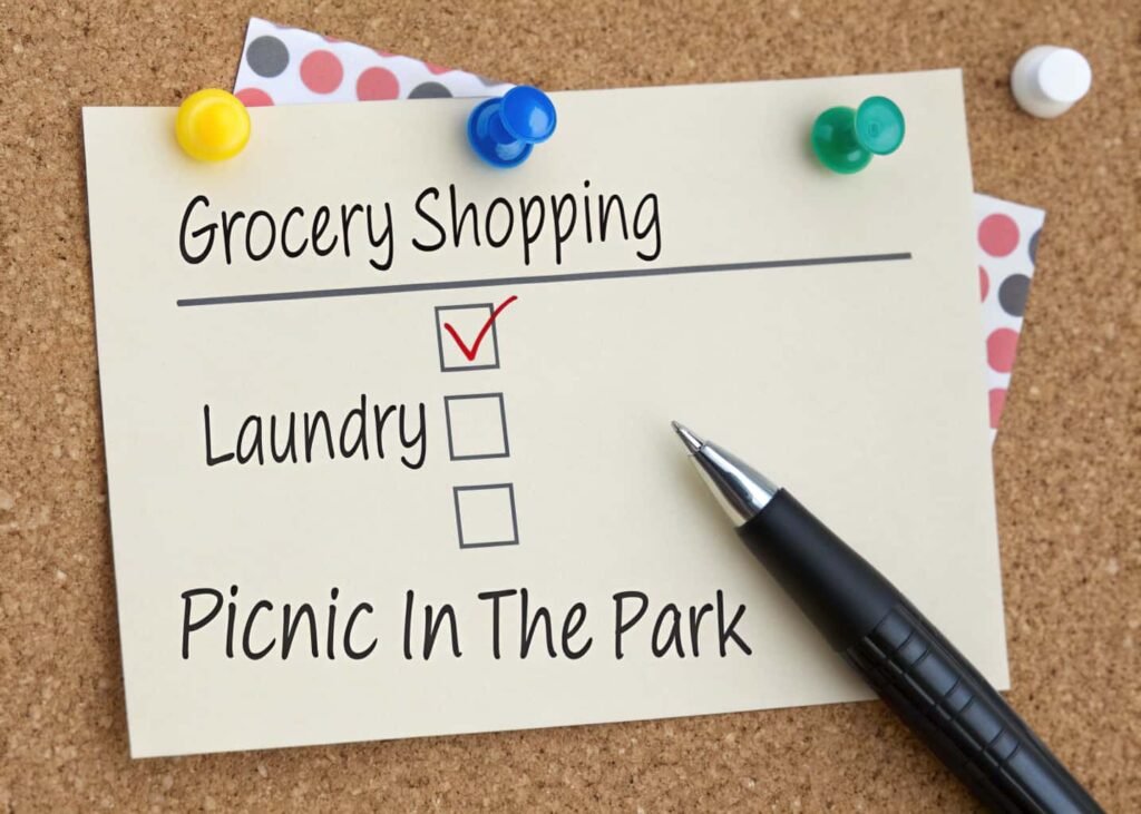 A simple printed weekend checklist pinned to a corkboard with tasks checked off in pen.