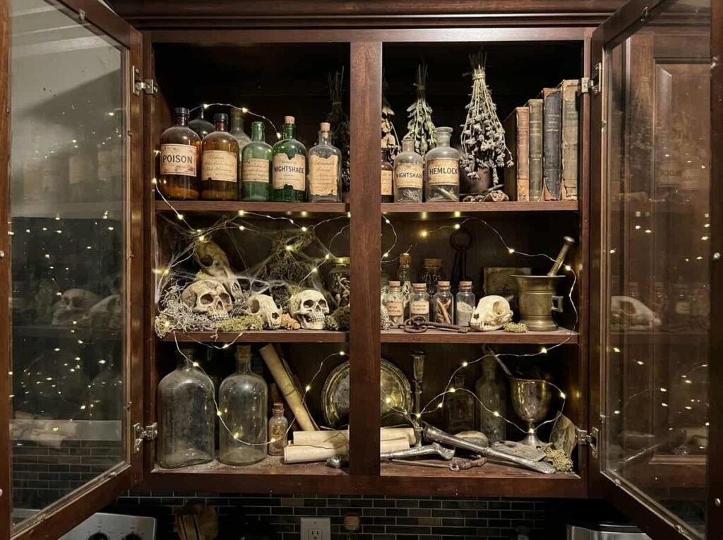 Glass kitchen cabinet decorated as a Halloween display case with skulls and bottles