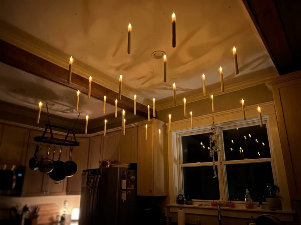 Floating candles hanging from a kitchen ceiling with a small skeleton decoration