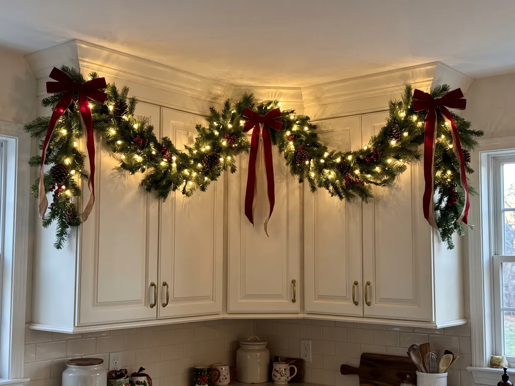 Kitchen cabinets with a lit garland swag and red ribbons