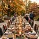 Outdoor Thanksgiving table on a patio at golden hour with string lights, lanterns and blankets on the chairs